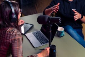 Interviewerin mit Kopfhörern und Mikrofon im Gespräch mit einem Mann